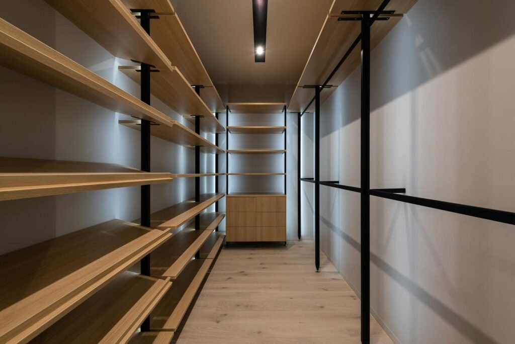 Explore a spacious modern walk-in closet with wooden shelves and sleek design, perfect for organizing.