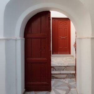 A hallway with a red door and a white wall
